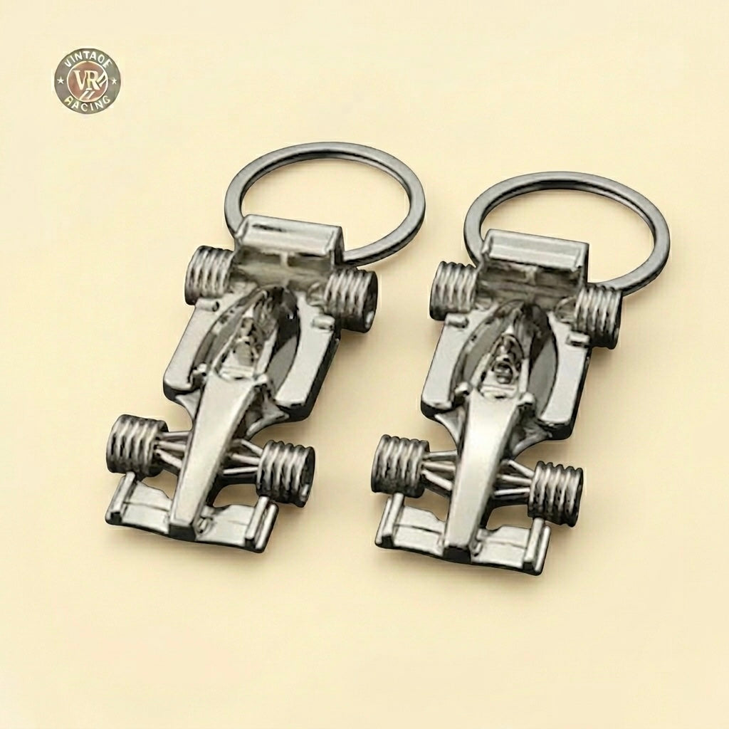 Two F1 Racing Car Keychains, shaped like Formula 1 cars, rest side by side on a beige surface. A circular Vintage Racing logo is in the top left corner—an ideal gift for any Formula 1 fan.