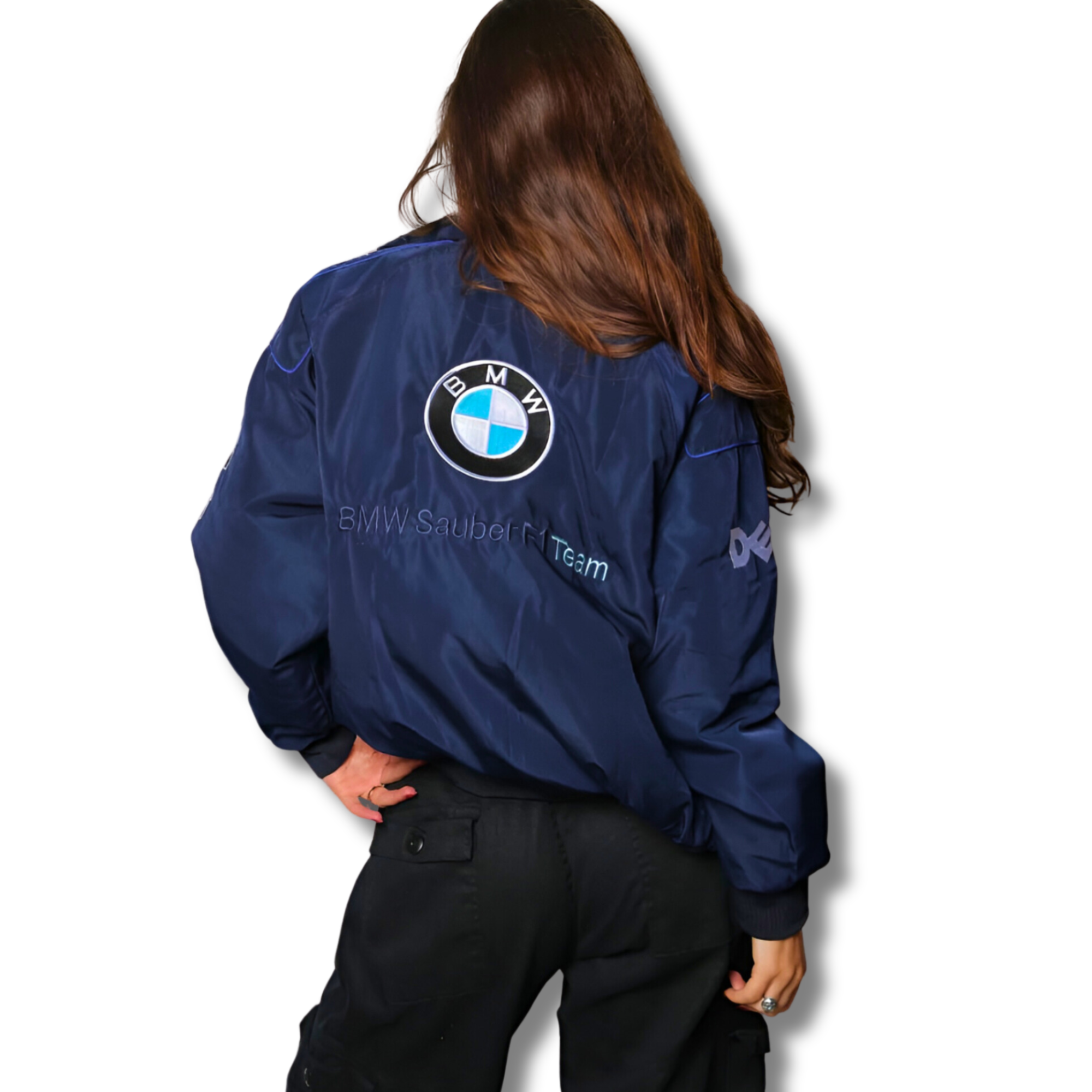 A person with long brown hair, wearing the BMW F1 Vintage Racing Jacket - Classic Edition in navy blue and black pants, stands with their back to the camera against a plain white background.