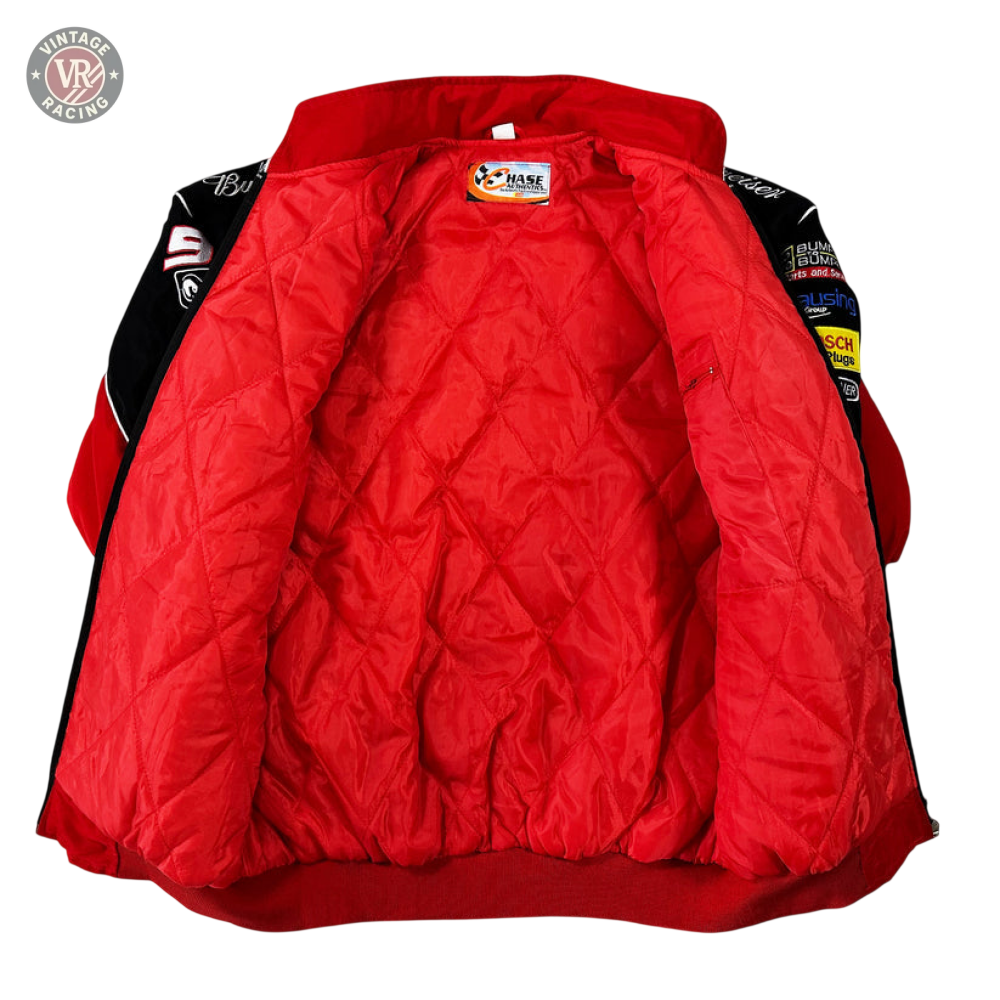 The Budweiser Racing Vintage Jacket - NASCAR Red Edition is displayed open on a white surface, showcasing its quilted red lining and multiple patches and logos on the sleeves and collar for an authentic vintage motorsport vibe.