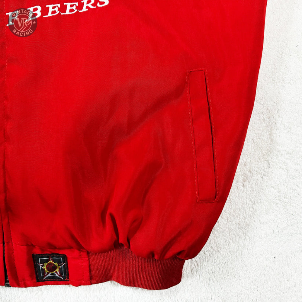 Close-up of the Budweiser Racing Vintage Jacket - NASCAR Red Edition showing a side pocket, gathered waistband, part of a star patch, and partial white F BEERS text against a white textured background.