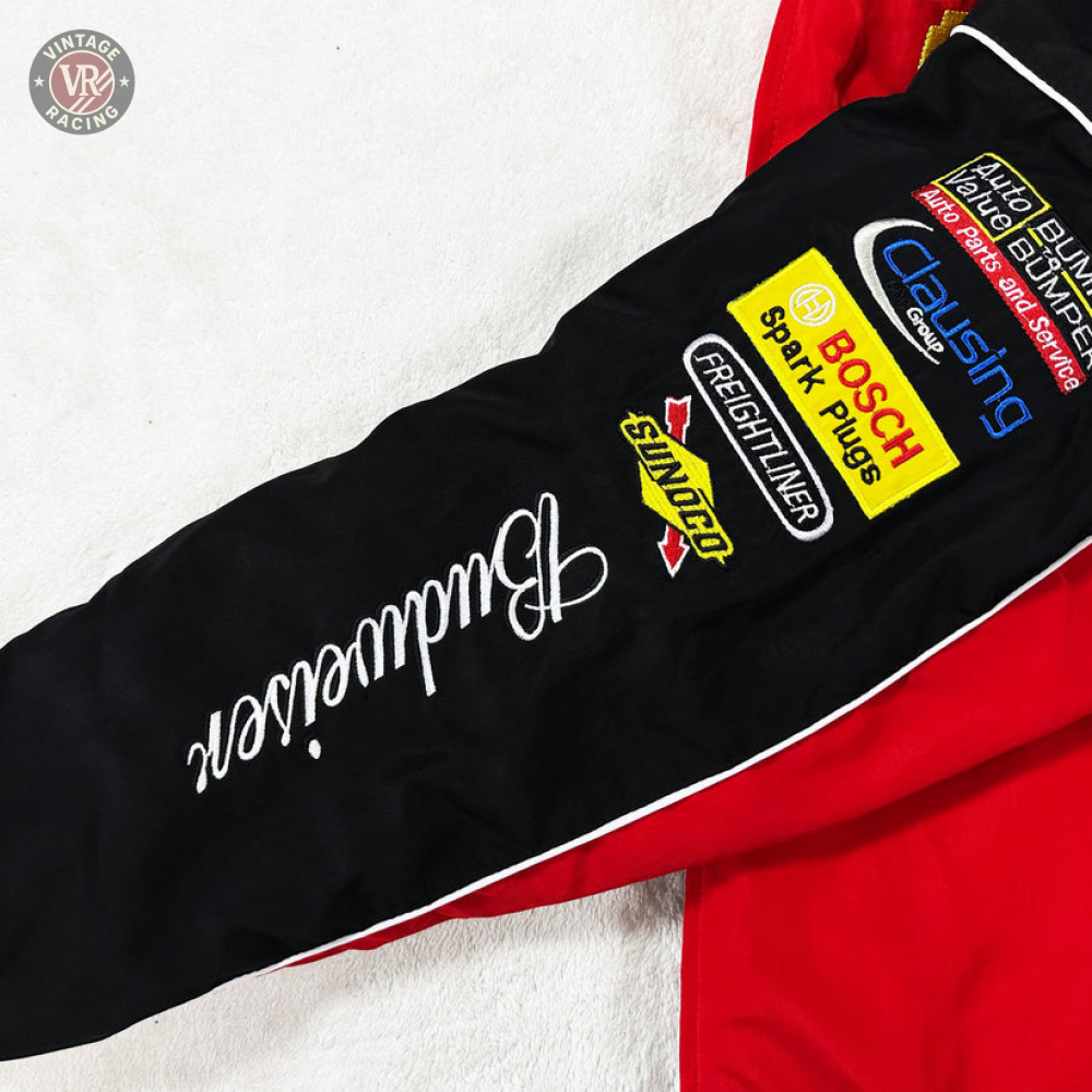 A close-up of the Budweiser Racing Vintage Jacket - NASCAR Red Edition sleeve, showing embroidered Budweiser, Bosch, Snap-on, Freightliner, and Clausing logos on black fabric with white piping and red accents for a classic motorsport look.