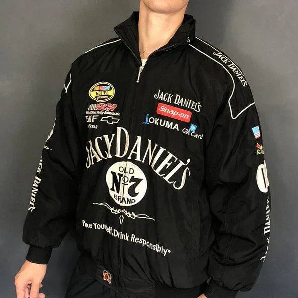 Someone wearing a Jack Daniel’s Racing Vintage Jacket, featuring sponsor logos and white text, stands against a plain dark background.