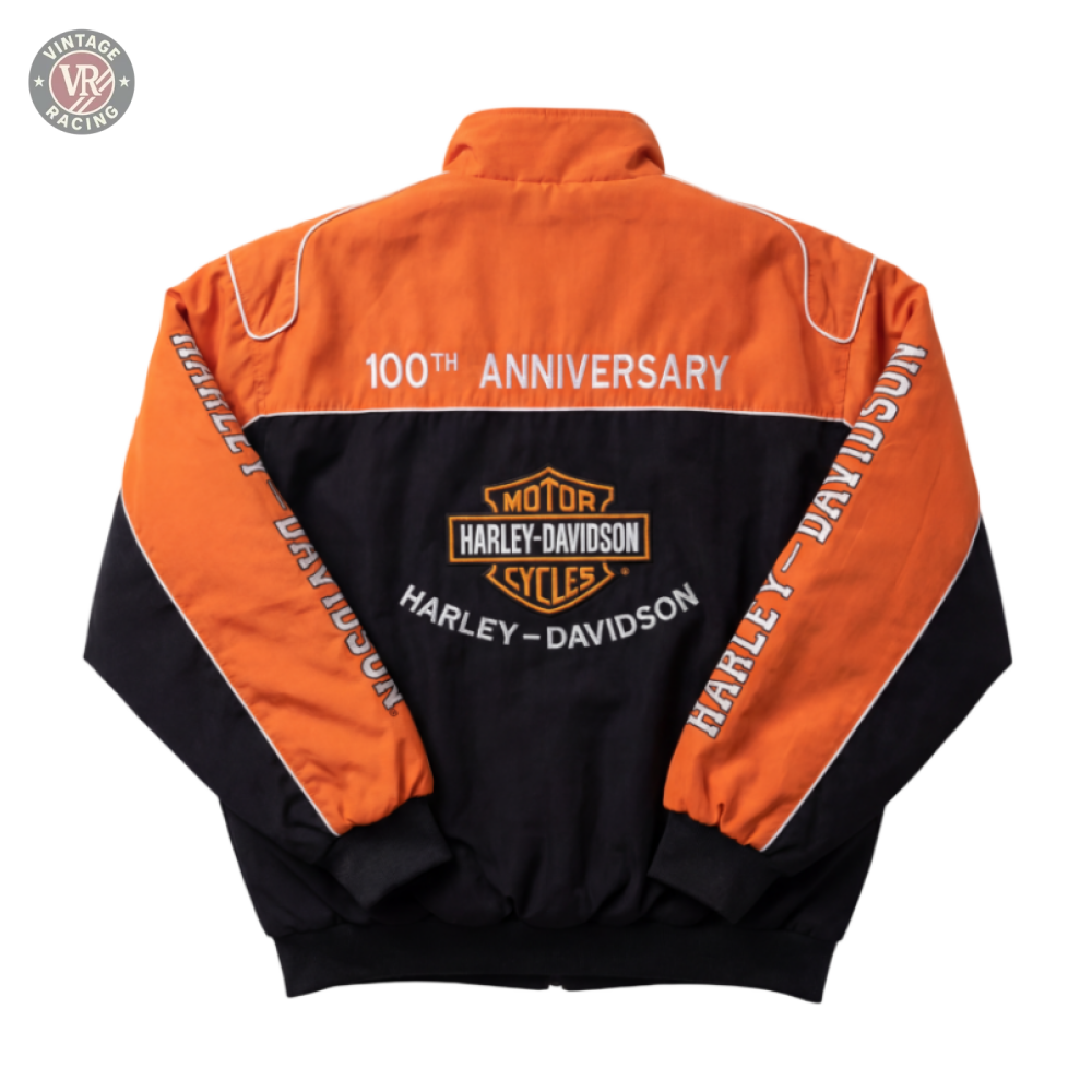 The Harley Davidson Vintage Racing Motorcycle Jacket features orange and black colors, “100th Anniversary” and “Harley-Davidson” text, an emblem on the back, and Harley-Davidson printed on the sleeves.