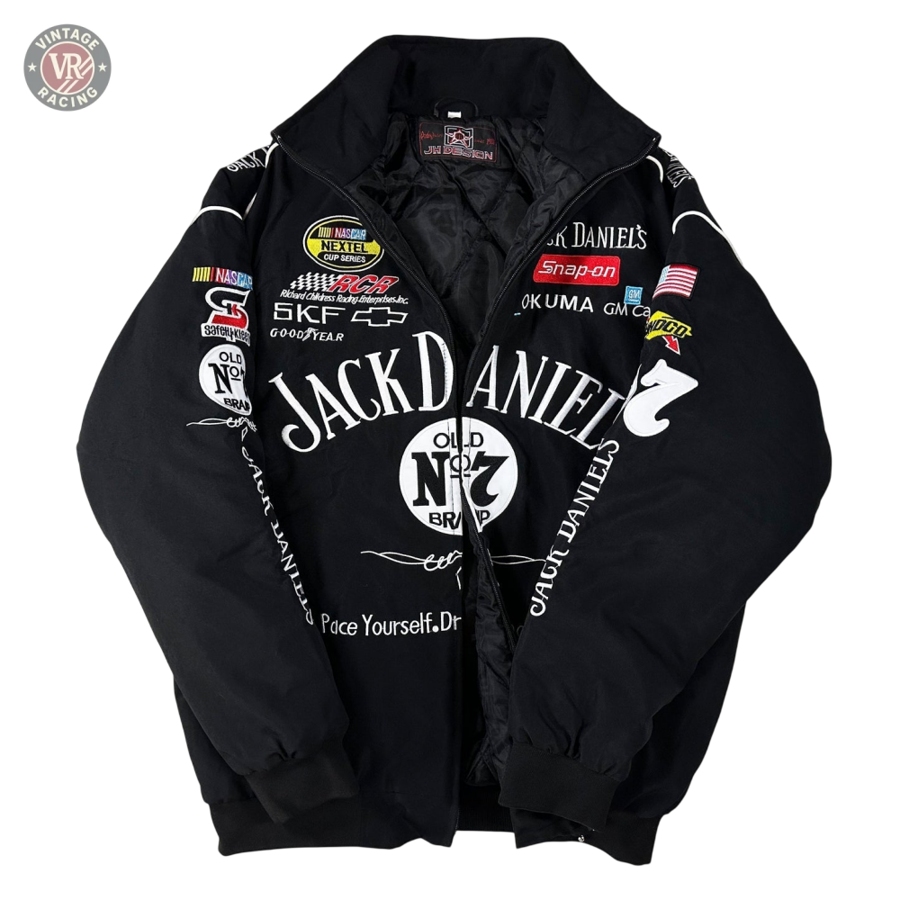 The Sponsored’s Racing Vintage Jacket is a black motorsport-style piece with colorful sponsor patches, including Jack Daniel’s Old No. 7 on the front, shown laid flat on a white surface.
