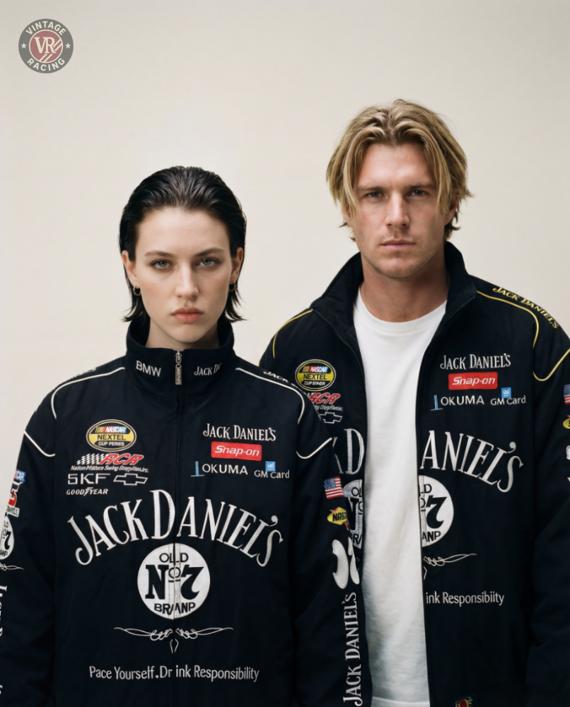 Two people stand side by side against a plain background, wearing matching black Sponsored’s Racing Vintage Jackets, looking directly at the camera with neutral expressions and showcasing motorsport-inspired contemporary streetwear.