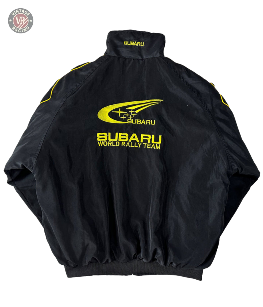 The Subaru Rally Vintage Racing Jacket features bold yellow logos and text on the back, a high collar, and elastic cuffs. The Subaru emblem and rally graphics highlight its authentic rally heritage.