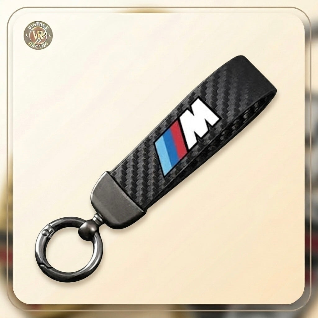 The BMW M Sport Keychain is a sleek black carbon fiber accessory with a metal keyring, featuring the iconic BMW M logo and blue, purple, and red stripes—ideal for any BMW M Sport enthusiast.