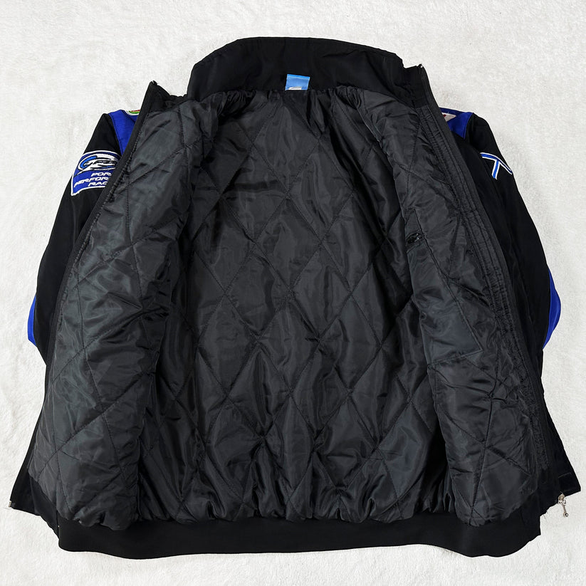 A Ford Vintage Jacket - Performance Edition in black is displayed open, showcasing its quilted lining and sleeves with blue and black panels accented by embroidered patches inspired by classic racing heritage.