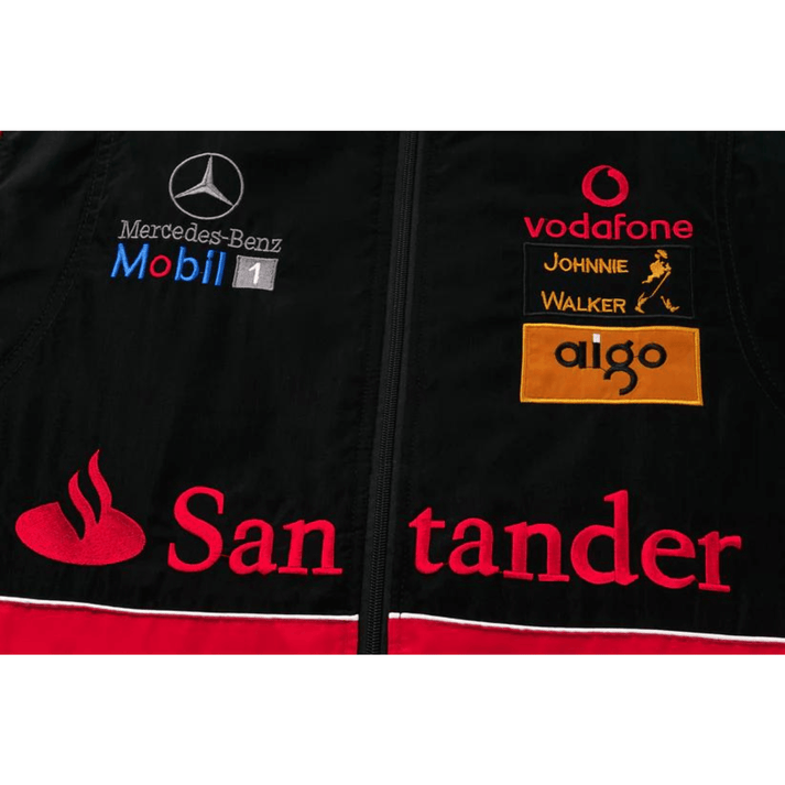 Close-up of the McLaren x Mercedes-Benz Vintage Jacket, a black Grand Prix jacket with Mercedes-Benz, Mobil 1, Vodafone, Johnnie Walker, aigo, and Santander logos plus red, white, and yellow embroidery—a Formula 1 streetwear classic.