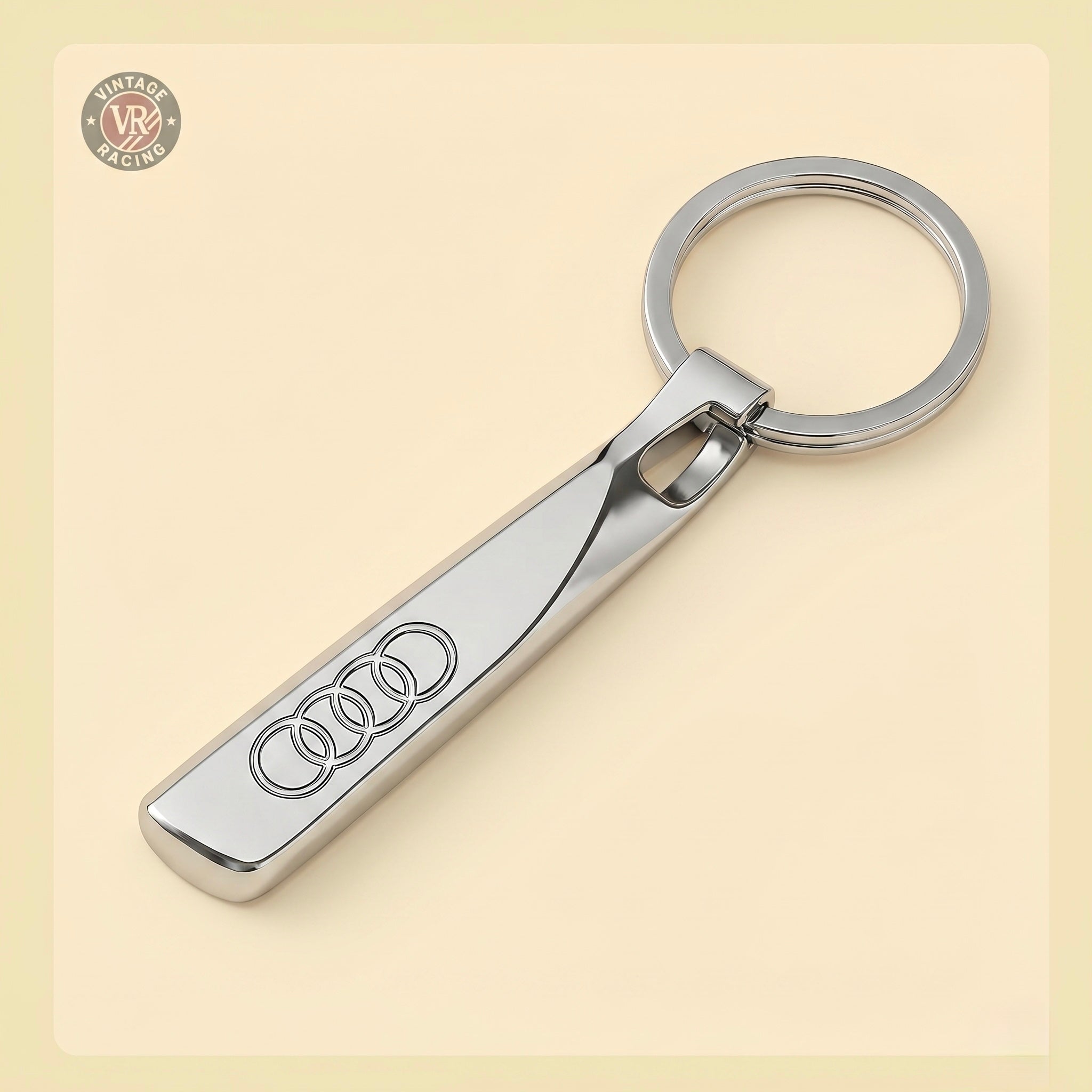 The Audi Keychain showcases the iconic four-ring logo in polished silver, offering a modern and elegant design against a light beige backdrop—an ideal accessory for any Audi enthusiast.