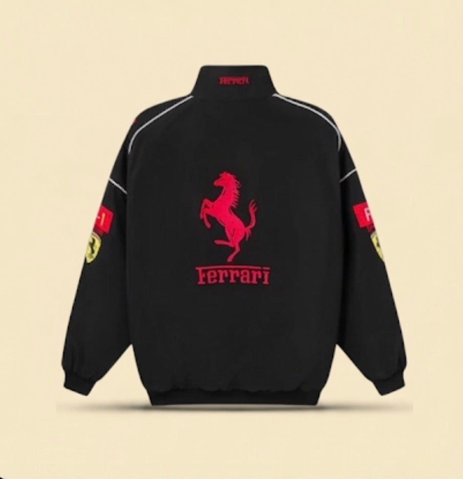 The F1 Vintage Ferrari Racing Jacket - Black Edition is shown from the back, displaying a bold red prancing horse and "Ferrari" text. Both sleeves feature red patches with yellow Ferrari logos, highlighting its retro motorsport style.