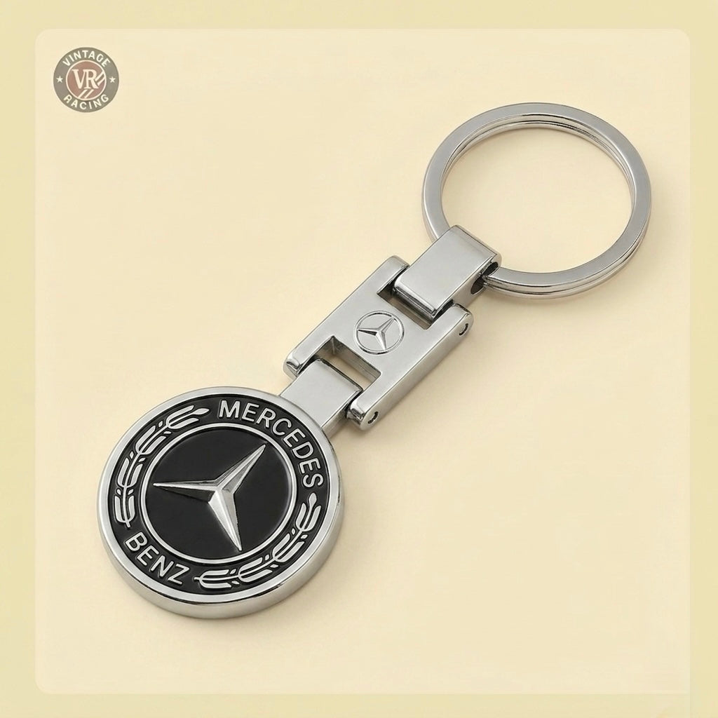 The Mercedes-Benz Keychain features the iconic round black and silver star logo on a sturdy metal keyring, making it perfect for car enthusiasts. Displayed on a light beige background.