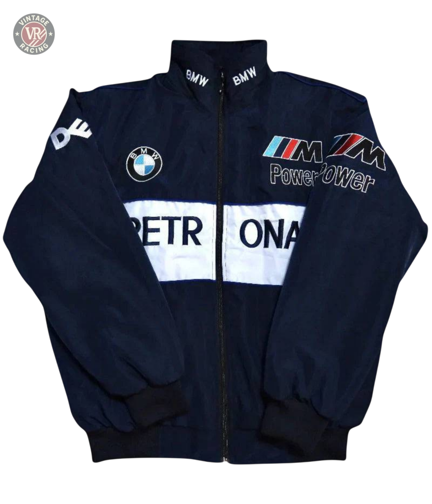 The BMW F1 Vintage Racing Jacket is navy blue with PETRONAS in white on the front, BMW and M Power logos on the chest, and BMW text on the collar. Features a zip-up front, black cuffs, and true racing heritage style.