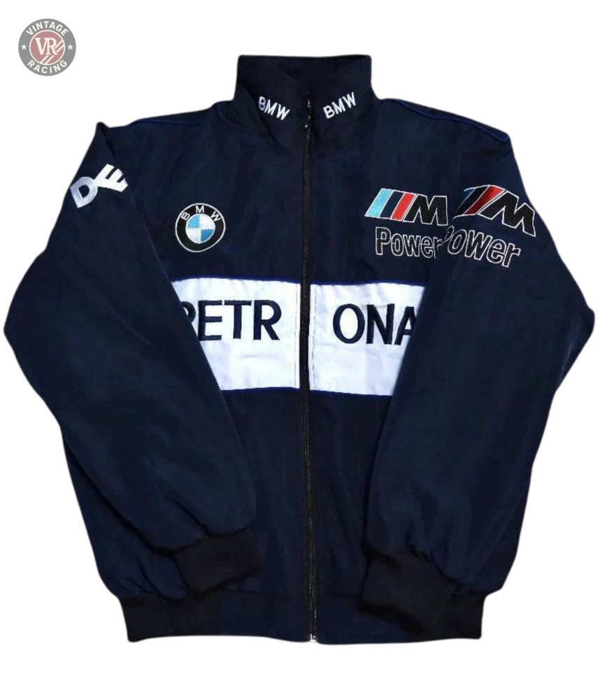 The BMW F1 Vintage Racing Jacket is navy blue with PETRONAS in white on the front, BMW and M Power logos on the chest, and BMW text on the collar. Features a zip-up front, black cuffs, and true racing heritage style.