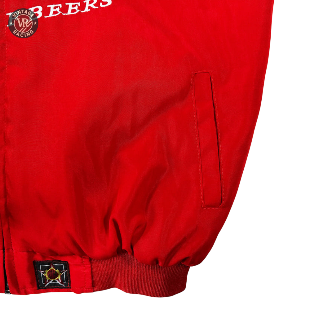 Close-up of the Budweiser Racing Vintage Jacket - NASCAR Red Edition showing a side pocket, gathered waistband, part of a star patch, and partial white F BEERS text against a white textured background.