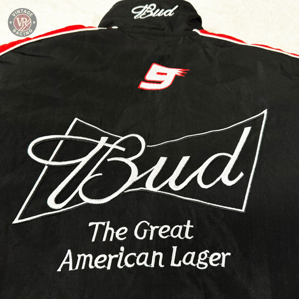 The Budweiser Vintage Racing Jacket - NASCAR Black Edition is a black jacket with red and white accents, featuring embroidered “Bud” in white, a red number 9, and the slogan “The Great American Lager.”.