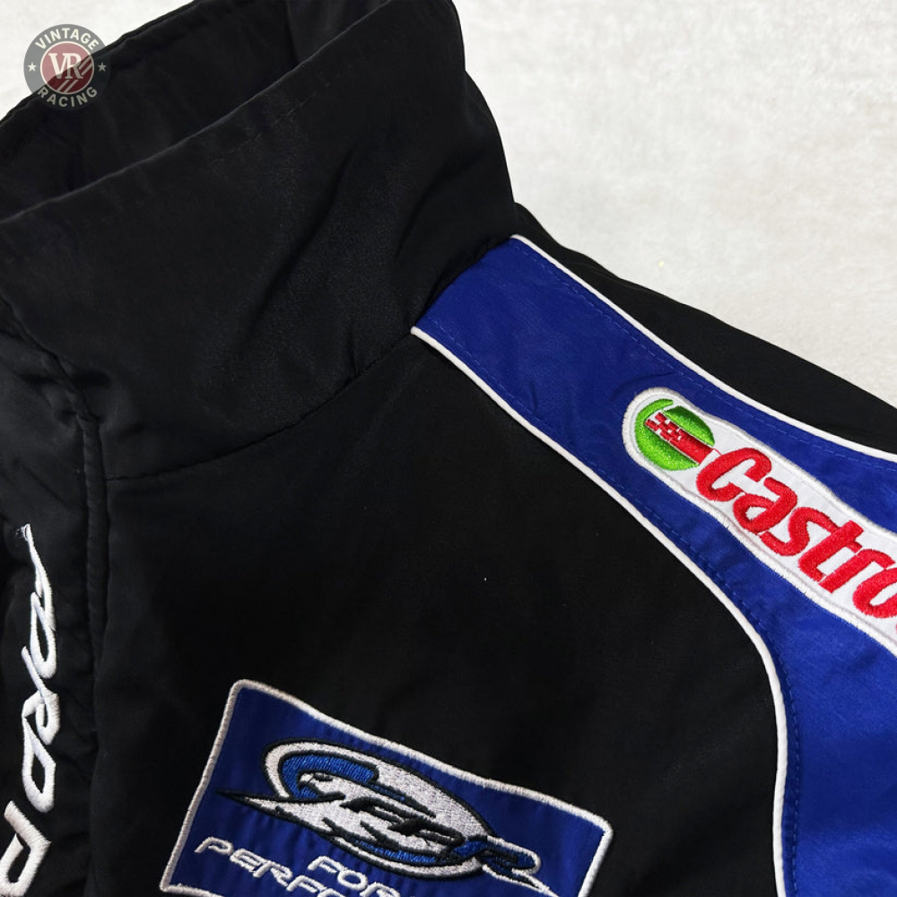 A close-up of the Ford Vintage Jacket - Performance Edition in black with blue and white details, showcasing embroidered Castrol and sponsor patches on the chest and shoulder—a tribute to racing heritage in streetwear style.