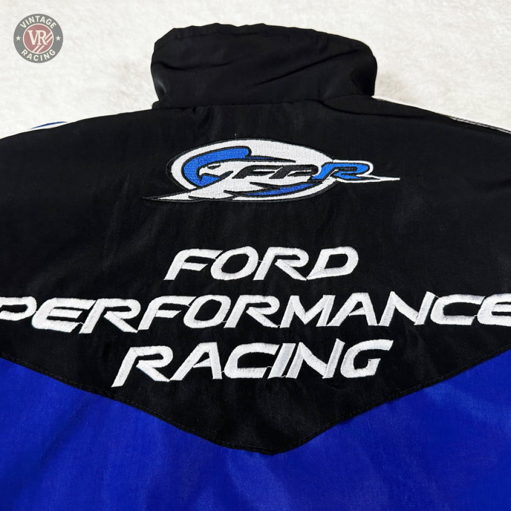 A close-up of the Ford Vintage Jacket - Performance Edition in black and blue, showing embroidered logos and Ford Performance Racing text in white and silver, celebrating racing heritage.