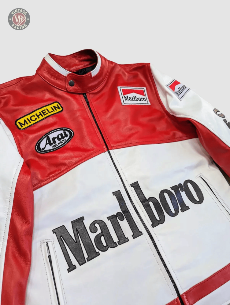 The Marlboro Racing Leather Jacket, shown on a light gray background, features bold red and white Marlboro branding with Michelin and Arai patches on the chest and arms for a classic retro motorsport look.