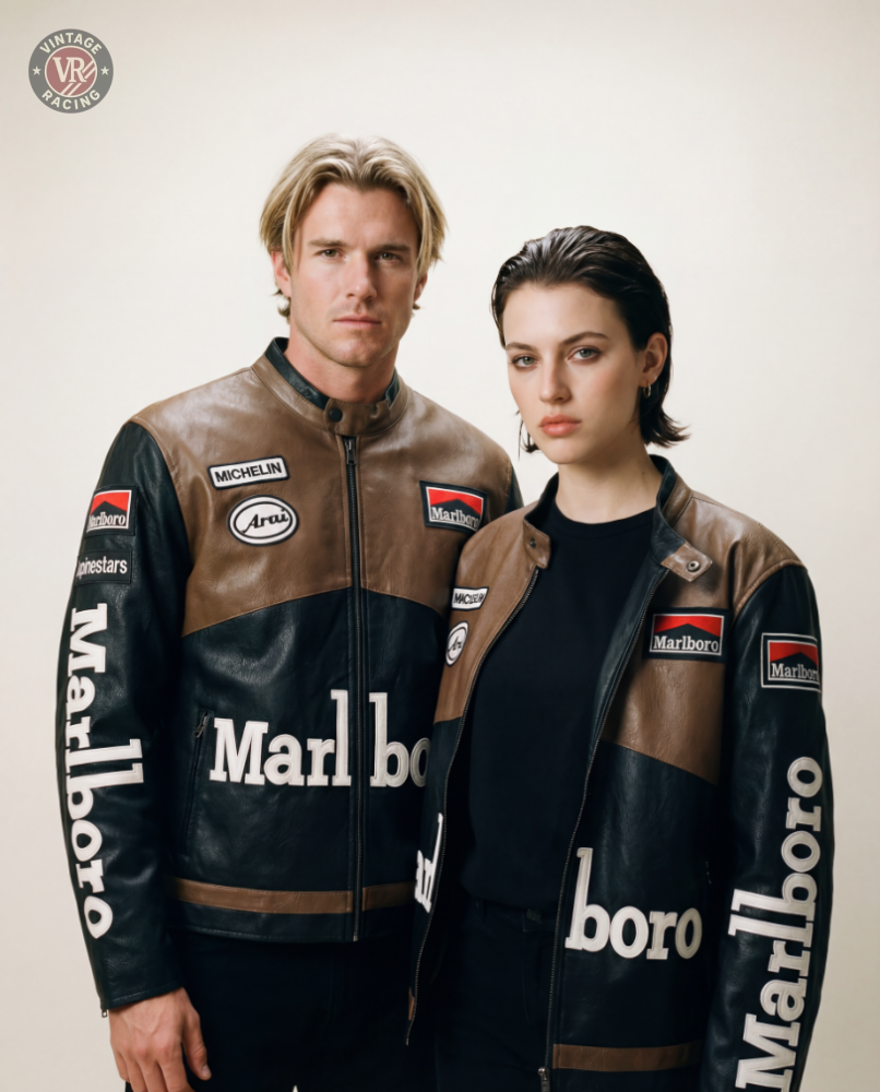 A man and a woman stand side by side wearing matching Marlboro Racing Leather Jacket - Retro Edition in brown and black leather with sponsor patches, set against a plain light background.