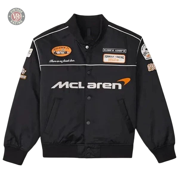 The McLaren Vintage Racing Bomber Black Jacket features a button-up front, ribbed cuffs, and patches such as the McLaren logo, Formula 1 Racing, plus orange and white emblems on the chest and sleeves.