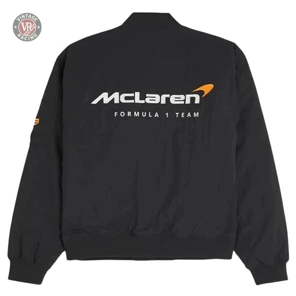The McLaren Vintage Racing Bomber Black Jacket features ribbed cuffs and waistband, with "McLaren FORMULA 1 TEAM" and the McLaren logo printed in white and orange on the back.