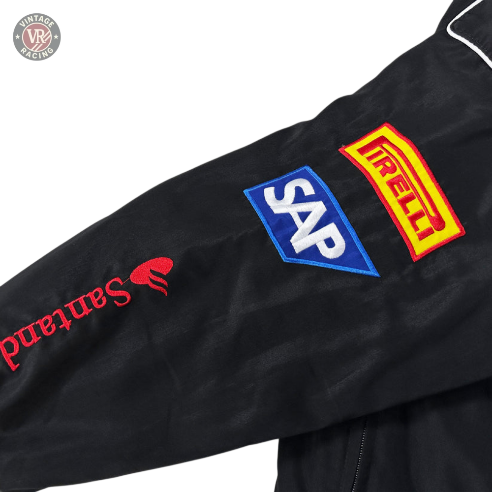 The Mercedes-Benz Santander Vintage Jacket’s black sleeve in stealth racing style showcases embroidered logos: Santander (red), SAP (blue/white), and Pirelli (yellow/red), all set against a light-colored background.
