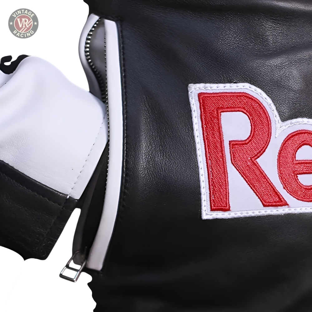Close-up of the Red Bull Leather Racing Jacket in black and white, featuring a white zipper and a red and white embroidered Re patch, showcasing its racing-inspired design.