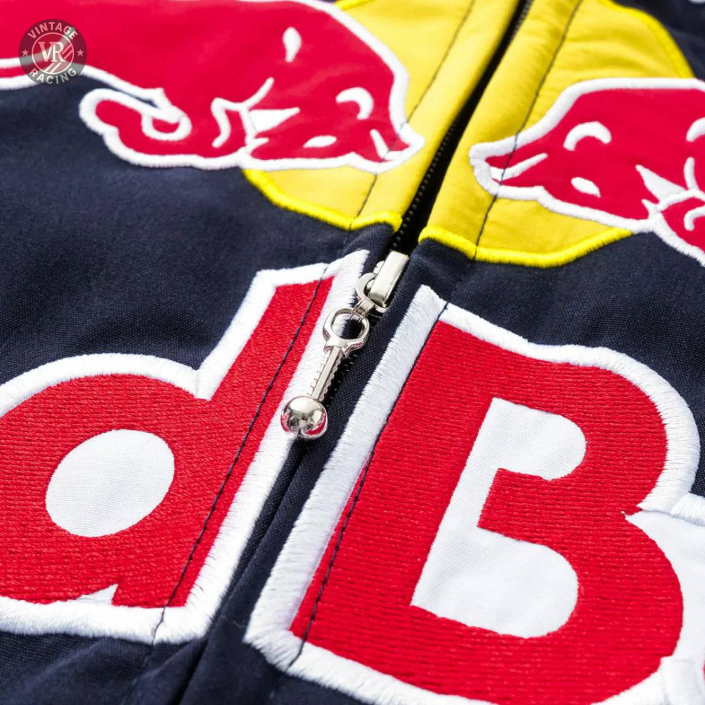 Close-up of the Red Bull Racing F1 Jacket zipper, showcasing embroidered red bulls, bold red and white d B letters on navy fabric, and a striking yellow background—an ideal addition to any Formula 1 fans apparel.
