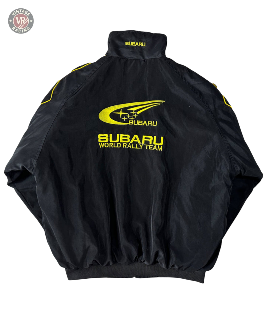 The Subaru Rally Vintage Racing Jacket features bold yellow logos and text on the back, a high collar, and elastic cuffs. The Subaru emblem and rally graphics highlight its authentic rally heritage.