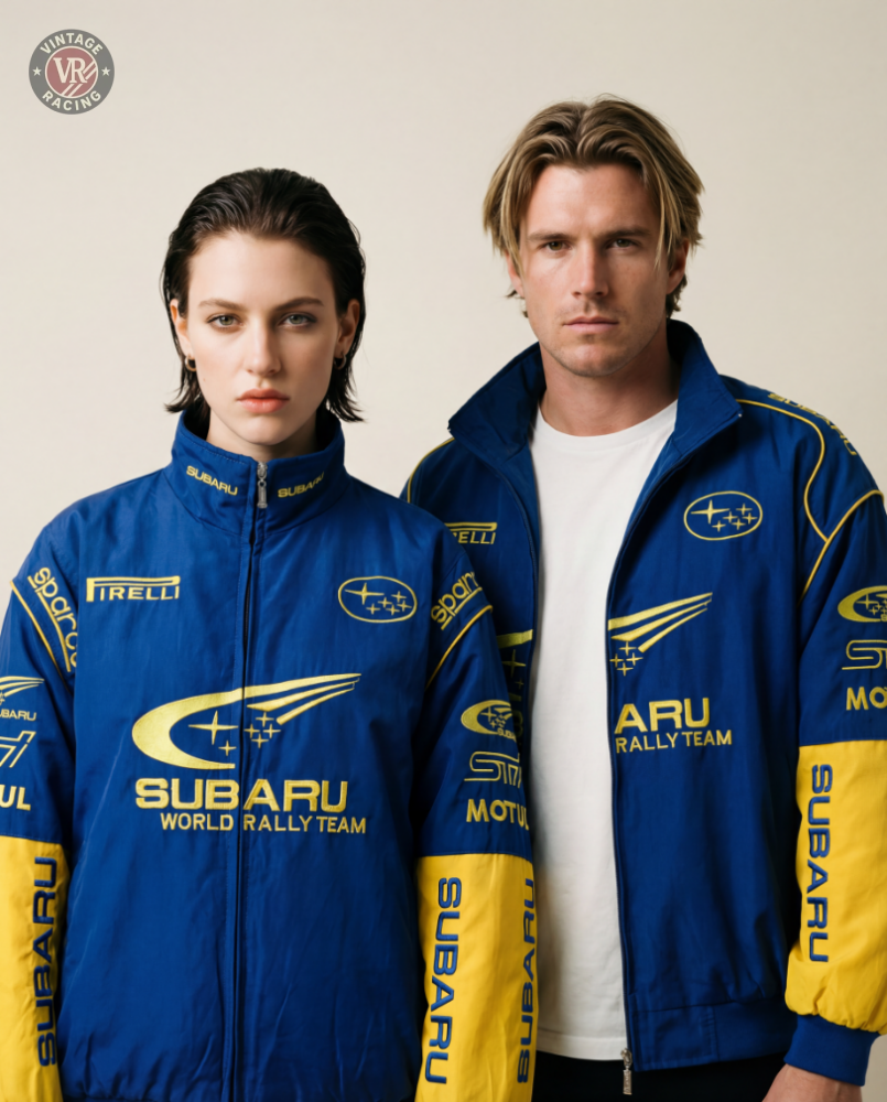 Two people wear Subaru World Rally Team Vintage Jackets, standing side by side against a plain background and looking directly at the camera with neutral expressions.