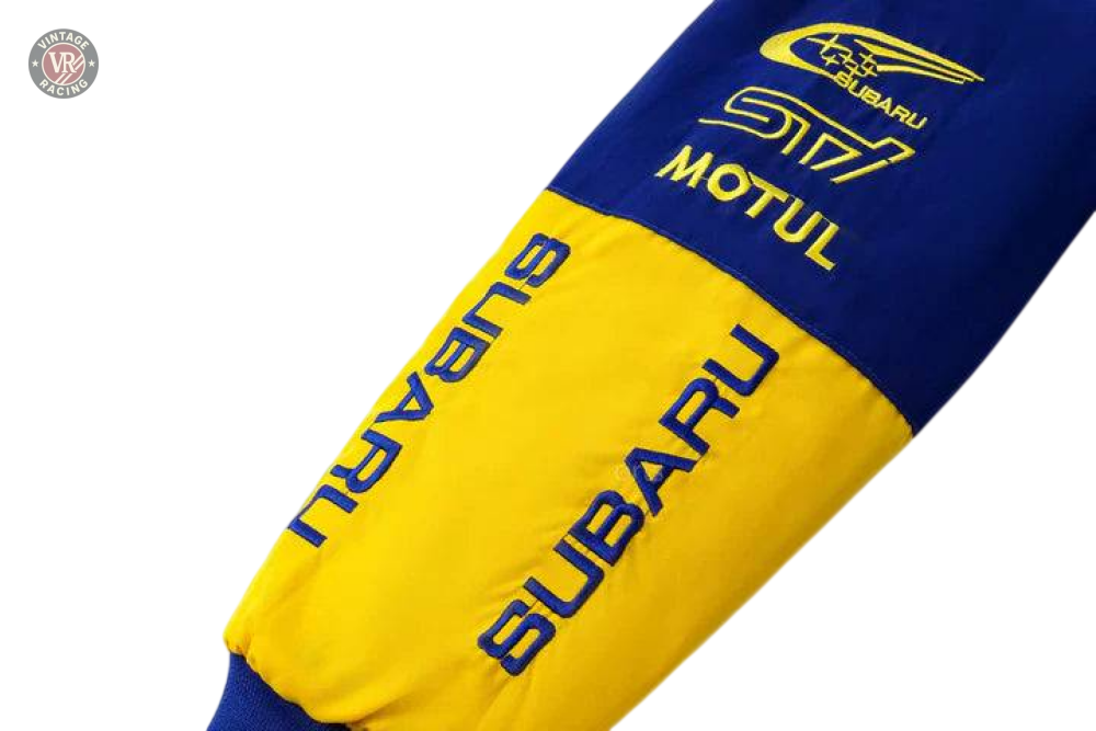 A close-up of the Subaru World Rally Team Vintage Jackets blue and yellow sleeve featuring SUBARU, MOTUL text, the rally car logo, and S17 print—evoking the iconic 555 livery.